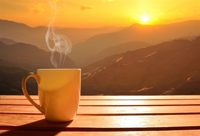 Investing in coffee: Image of a coffe mug over rising mountain sun