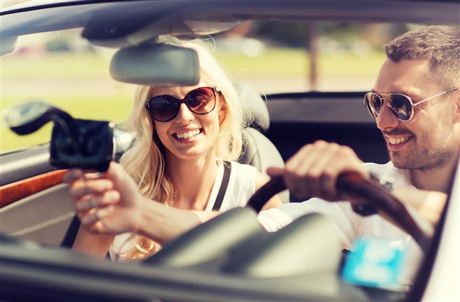 photo of happy man and woman driving car and using gps navigation system