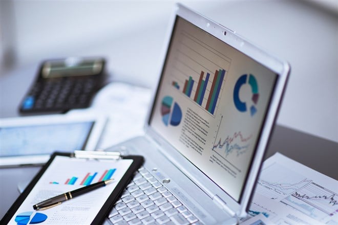 Businessman analyzing investment charts with laptop.