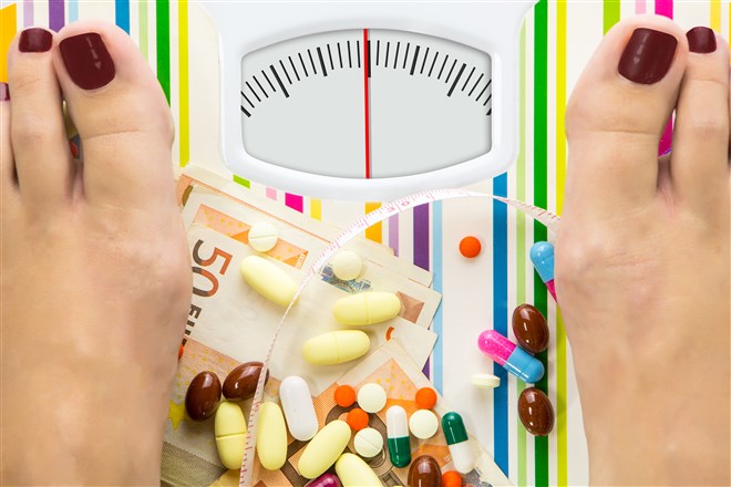 Photo of scale with women's feet on it and series of drug capsules