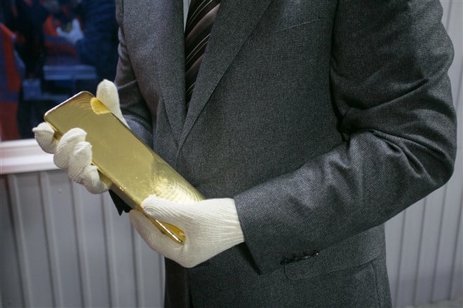 image of man with white gloves holding gold bar