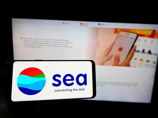 mobile phone with sea logo in front of laptop displaying Sea Limted's website