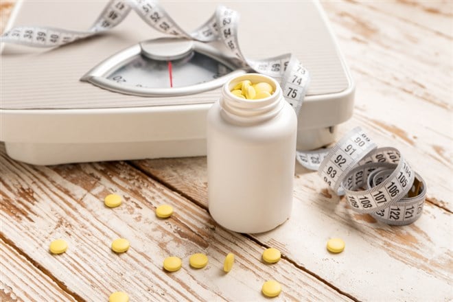 Bottle with weight loss pills, scales and measuring tape 