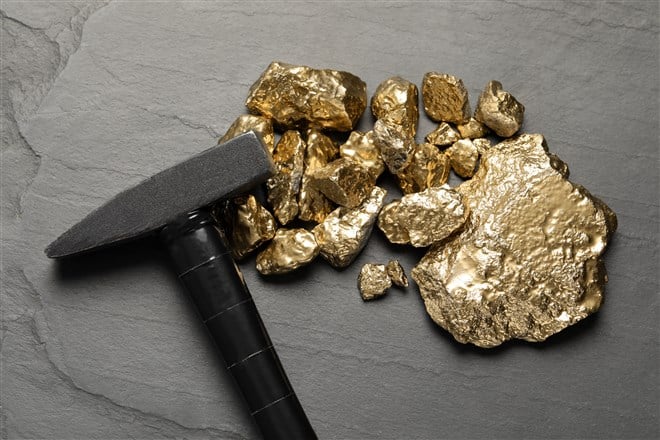 Picture of pile of gold nuggets and hammer on black background