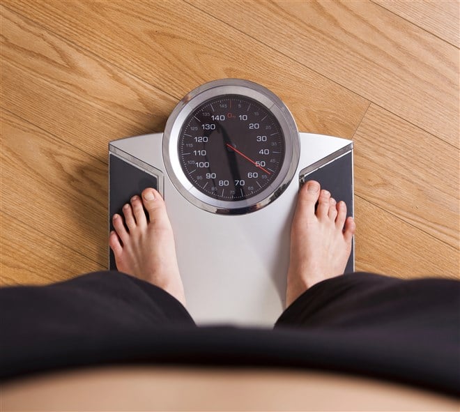 photo of man's feet standing on scale representing weight loss