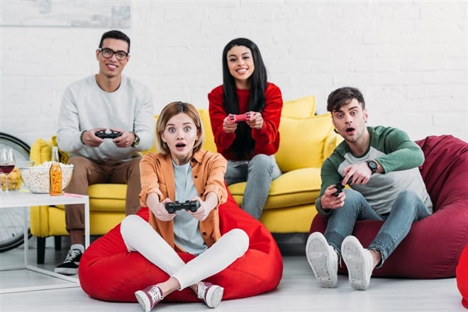 Photo of a group of people playing video games. Electronic Arts and Take-Two are two companies benefitting from a video gaming rebound.