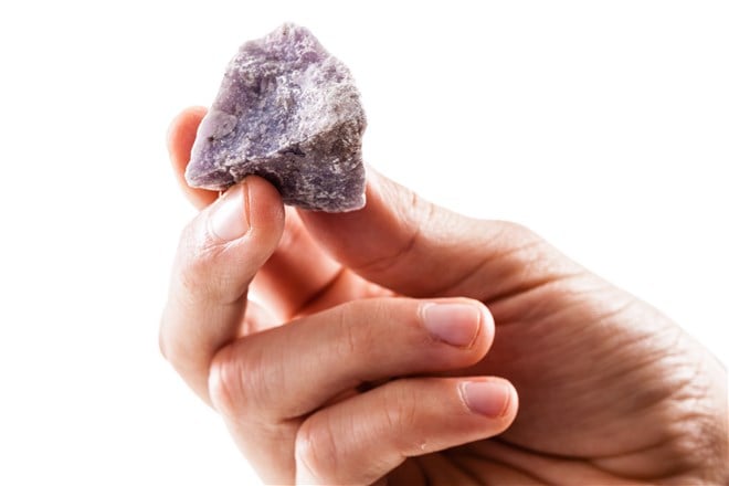 a male hand holding a fragment of lithium on a white background