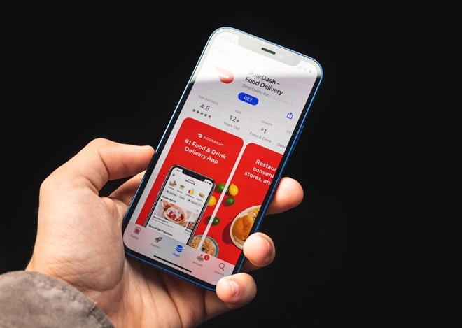 Photo of someone holding a phone with the DoorDash app open. With a 65% market share, DoorDash is the nation's largest food delivery service - should you buy the dip?