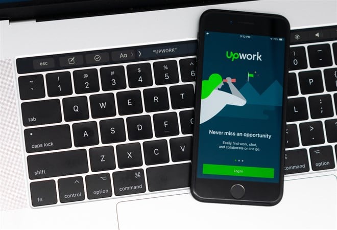 Photo of the Upwork for Freelancers mobile app login page on a smartphone laying on keyboard. Upwork Thrives in the Expanding AI Gig Economy