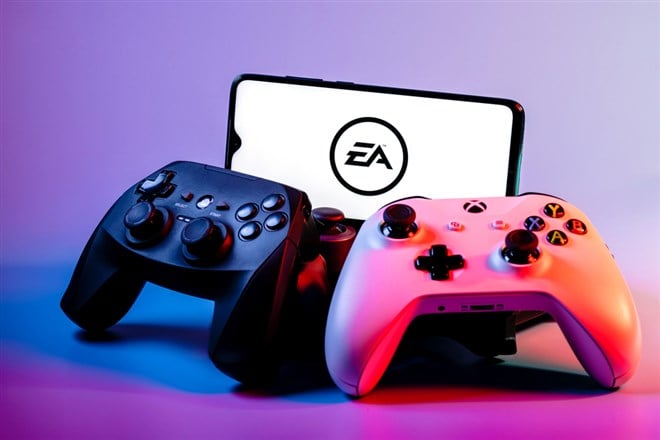 Photo of video game controllers and a smartphone showing the Electronic Arts logo. EA Q2 earnings engages players and builds value.