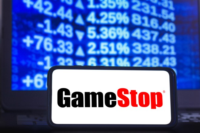 In this photo illustration a GameStop logo seen displayed on a smartphone with the stock market graphic in the background