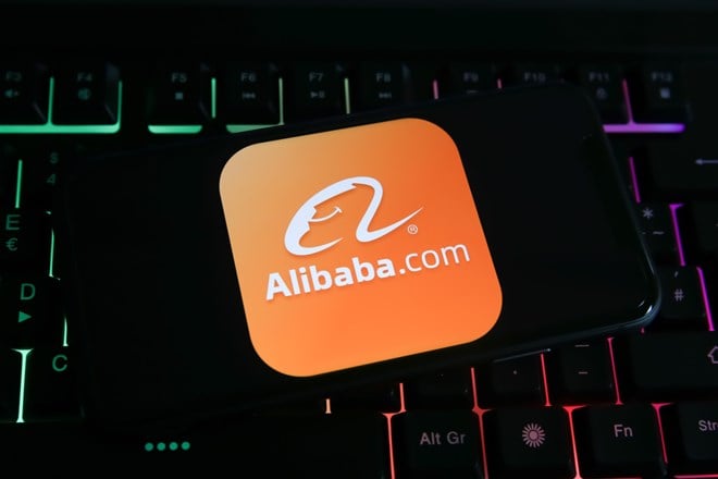 Closeup of mobile phone screen with logo lettering of alibaba.com on computer keyboard