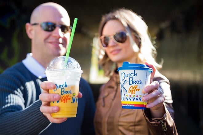 Photo of a couple holding cups of Dutch Bros coffee