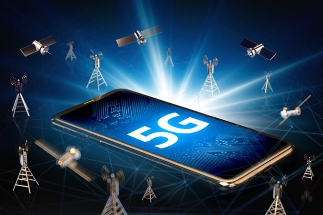 Smartphone with 5G sign on the screen laying down surrounded by network towers, satellites and high speed network nodes lines