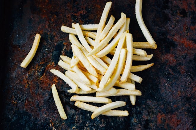 Lot of frozen potatoes fry on black rust background — Photo