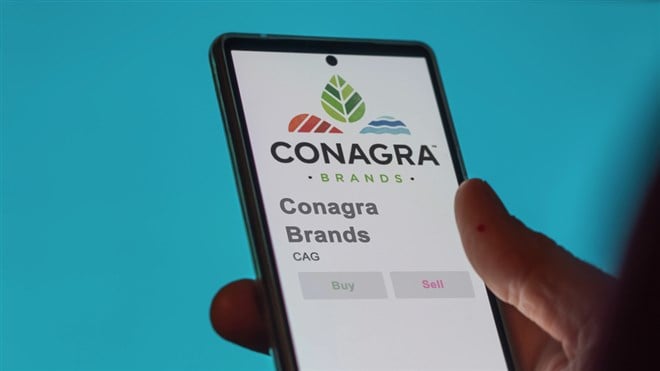 Close up on logo of Conagra Brands on the screen of an exchange. Conagra Brands price stocks, $CAG on a device.
