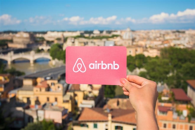 Airbnb logo on a business card, held up against a scenic overlook.
