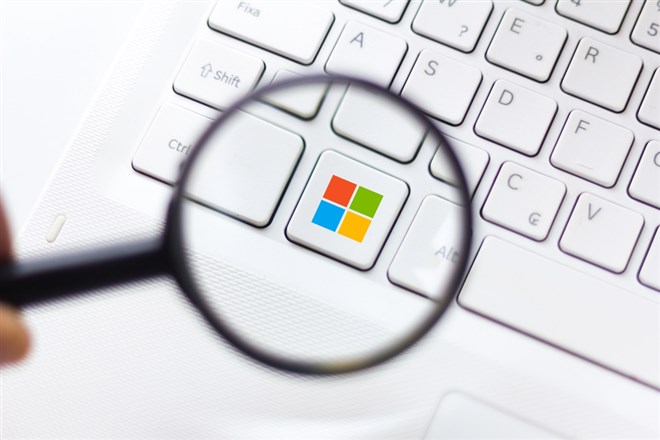 Microsoft Windows logo displayed on keyboard through a magnifying glass,