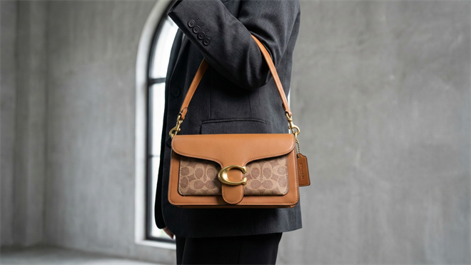 Person wearing a brown leather Coach-style shoulder bag, displaying the impressive performance of the Coach brand.