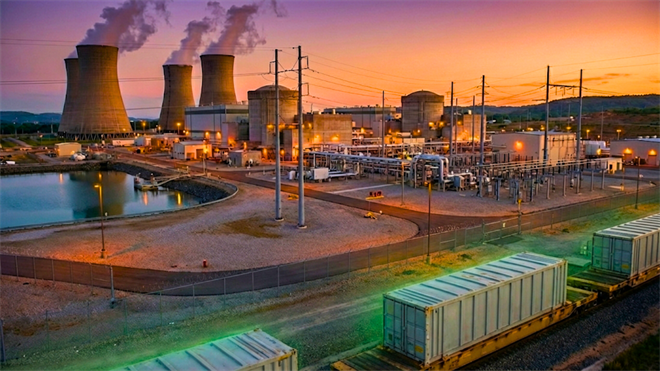 Nuclear power plant at dusk with cooling towers and rail cars, highlighting uranium demand and energy market focus.