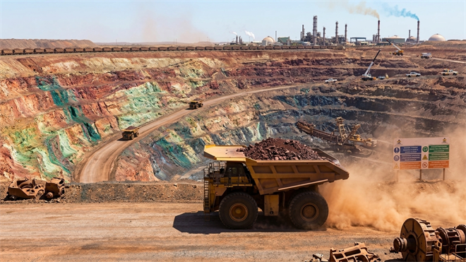 Open-pit rare-earths mine with haul trucks and processing plant.