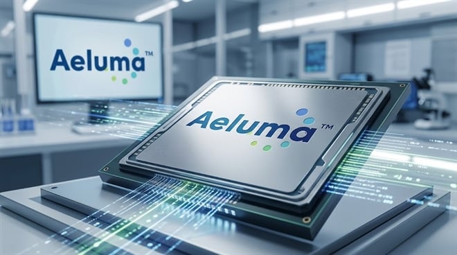 Aeluma logo displayed on a semiconductor chip in a laboratory setting.