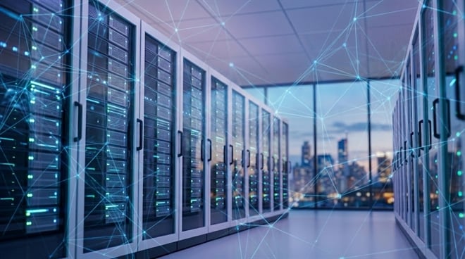 Rows of illuminated server racks line a data center with a city skyline visible in the background.