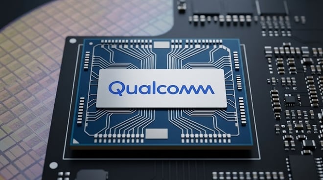A Qualcomm-branded semiconductor chip positioned on a circuit board and silicon wafer.
