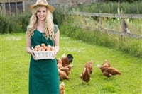 Photo of a woman carrying a basket of eggs from the free range chickens behind her. Vital Farms is capitalizing on the rising demand for pasture-raised eggs.