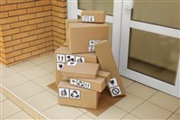 Cardboard boxes with different packaging symbols on door mat near entrance. Parcel delivery