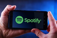 Picture of man's hands holding smartphone with Spotify logo displayed