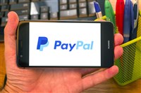 Mobile phone with PayPal on the screen, office background.