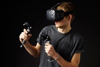 Photo of a young man wearing a virtual reality headset and using controllers. How to invest in virtual reality.