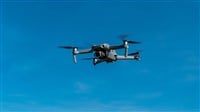 A modern drone flying in the cloudy blue sky — Photo