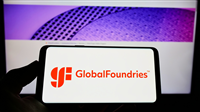 Person holding cellphone with logo of US semiconductor company GlobalFoundries Inc. (GF) on screen in front of webpage. Focus on phone display.