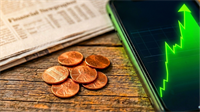 Penny coins beside a smartphone with rising green chart.