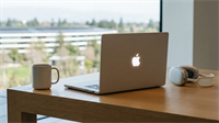 Macbook open on a table, positioned near other Apple products, representing a Apple device sales growth.
