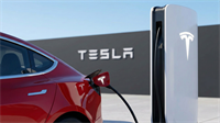 Red Tesla EV plugged into a Supercharger with Tesla logo, highlighting the company’s EV business pivot.
