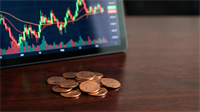 Tablet displaying a volatile stock chart with green and red candlesticks, coins stacked in foreground representing penny stocks.