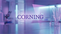Corning logo displayed on a transparent glass panel inside a modern lab environment, symbolizing AI infrastructure and optical connectivity.