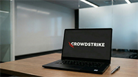 Laptop displaying CrowdStrike logo on screen in a modern office setting, representing AI-powered cybersecurity and industry growth.