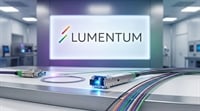 Fiber optic networking gear in a lab with the Lumentum logo shown prominently on a large background display.