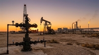 An oil field at sunset featuring a wellhead, pump jack, drilling rig, and refinery with a gas flare.
