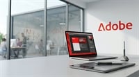 Adobe logo on an office wall beside a laptop displaying design software and a graphics tablet.