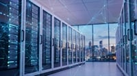 Rows of illuminated server racks line a data center with a city skyline visible in the background.