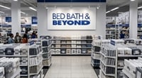 Interior of a Bed Bath and Beyond retail store with shoppers browsing shelves stocked with bedding products.