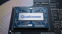 A Qualcomm-branded semiconductor chip positioned on a circuit board and silicon wafer.