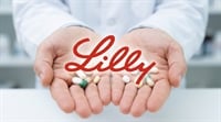 Eli Lilly logo overlaid on a person in a white coat holding assorted pills and capsules.