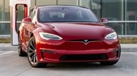 A red Tesla Model S electric sedan parked at a Tesla Supercharger station.