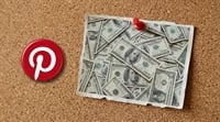 Pinterest logo pinned to a corkboard beside a note covered in U.S. hundred-dollar bills.